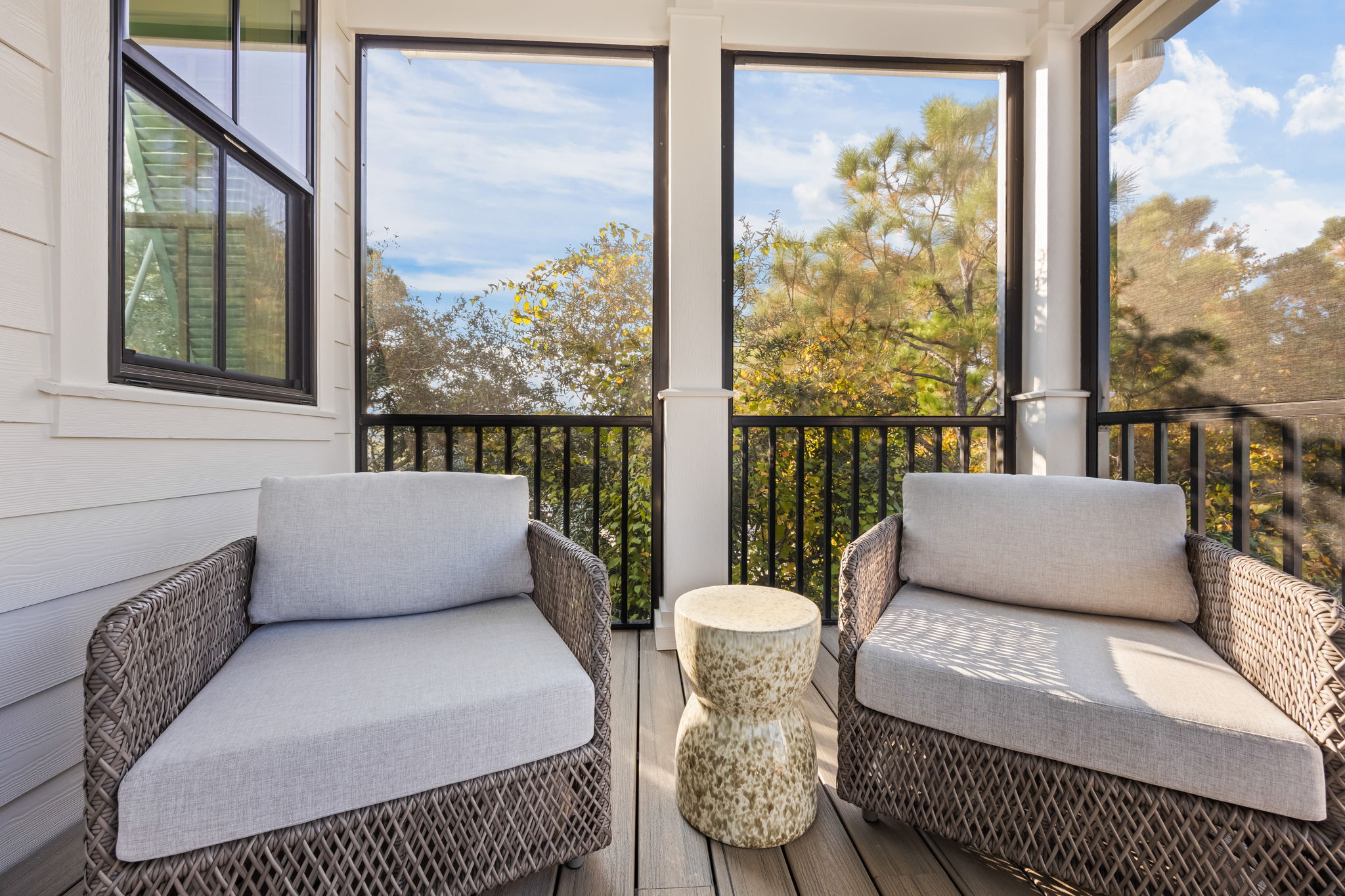A cozy seating area on the same screened porch offers a quiet spot for morning coffee or evening conversation. Comfortable lounge chairs and a side table create an inviting retreat just steps from the dining space.
