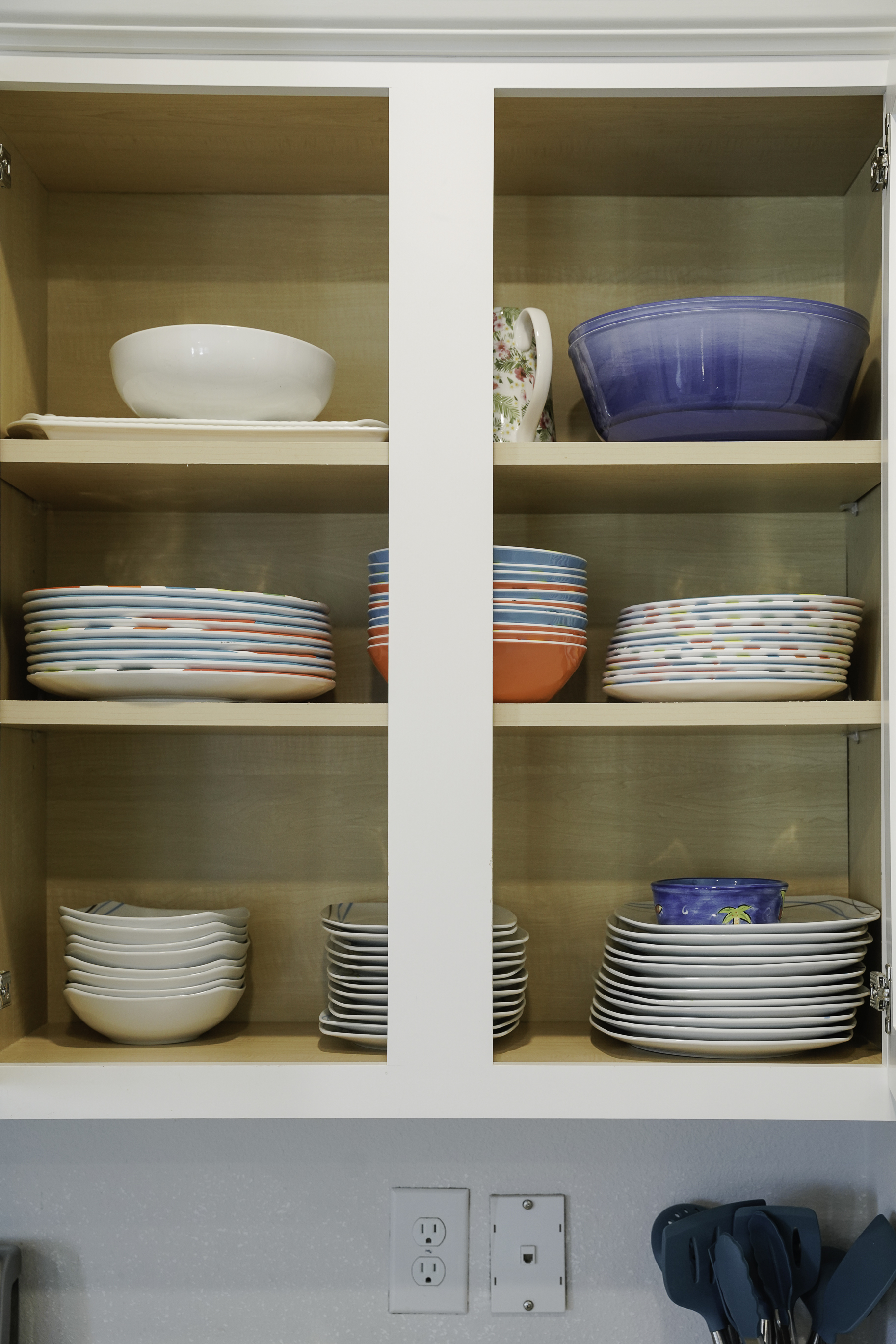 Fully stocked kitchen with utensils, plates, cups, and glasses