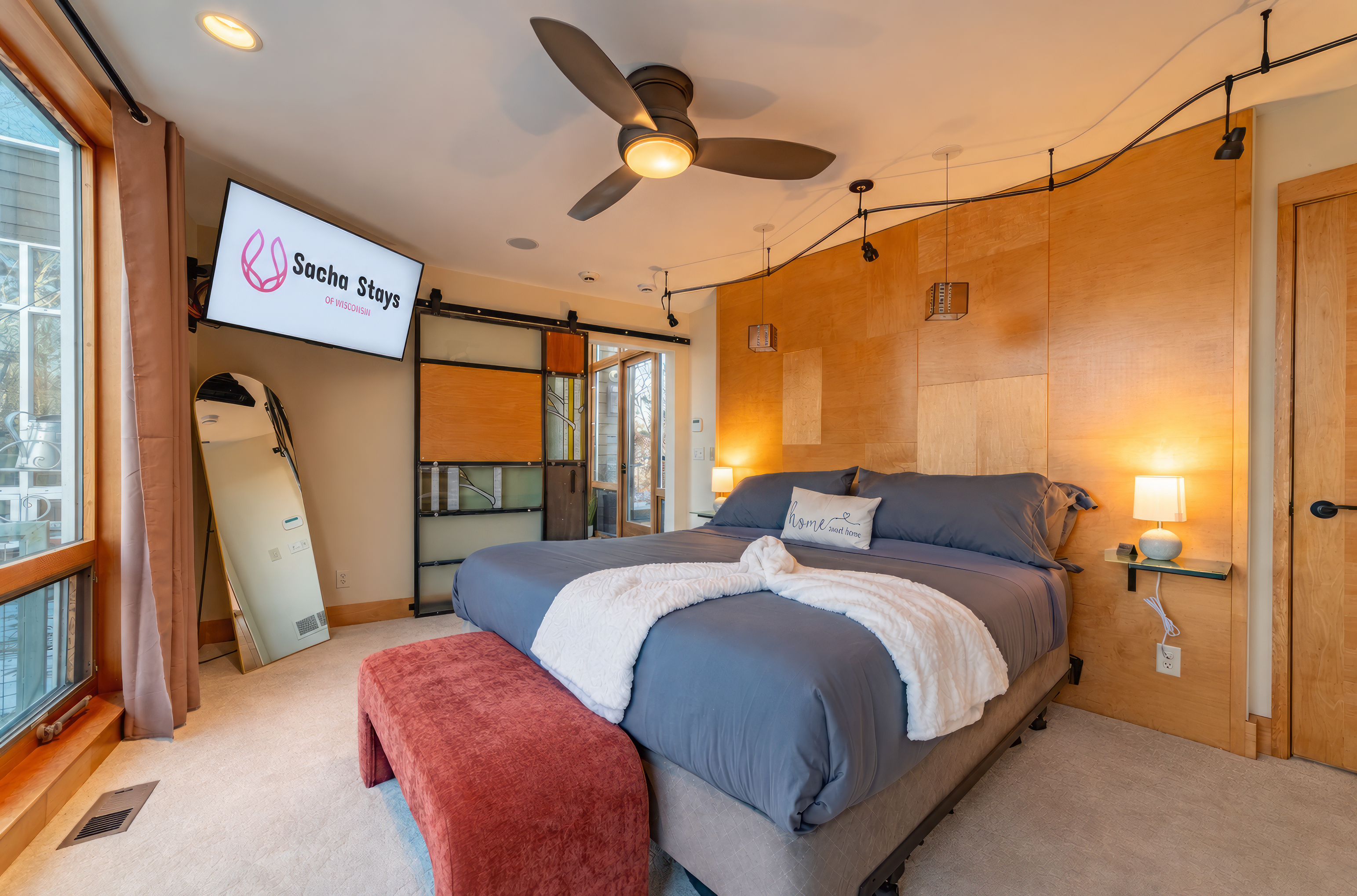 The main level master suite features a luxury King bed, 50" smart TV, floor to ceiling windows, en suite closet and bathroom with tub, dual rain shower, dual vanity, and heated floors