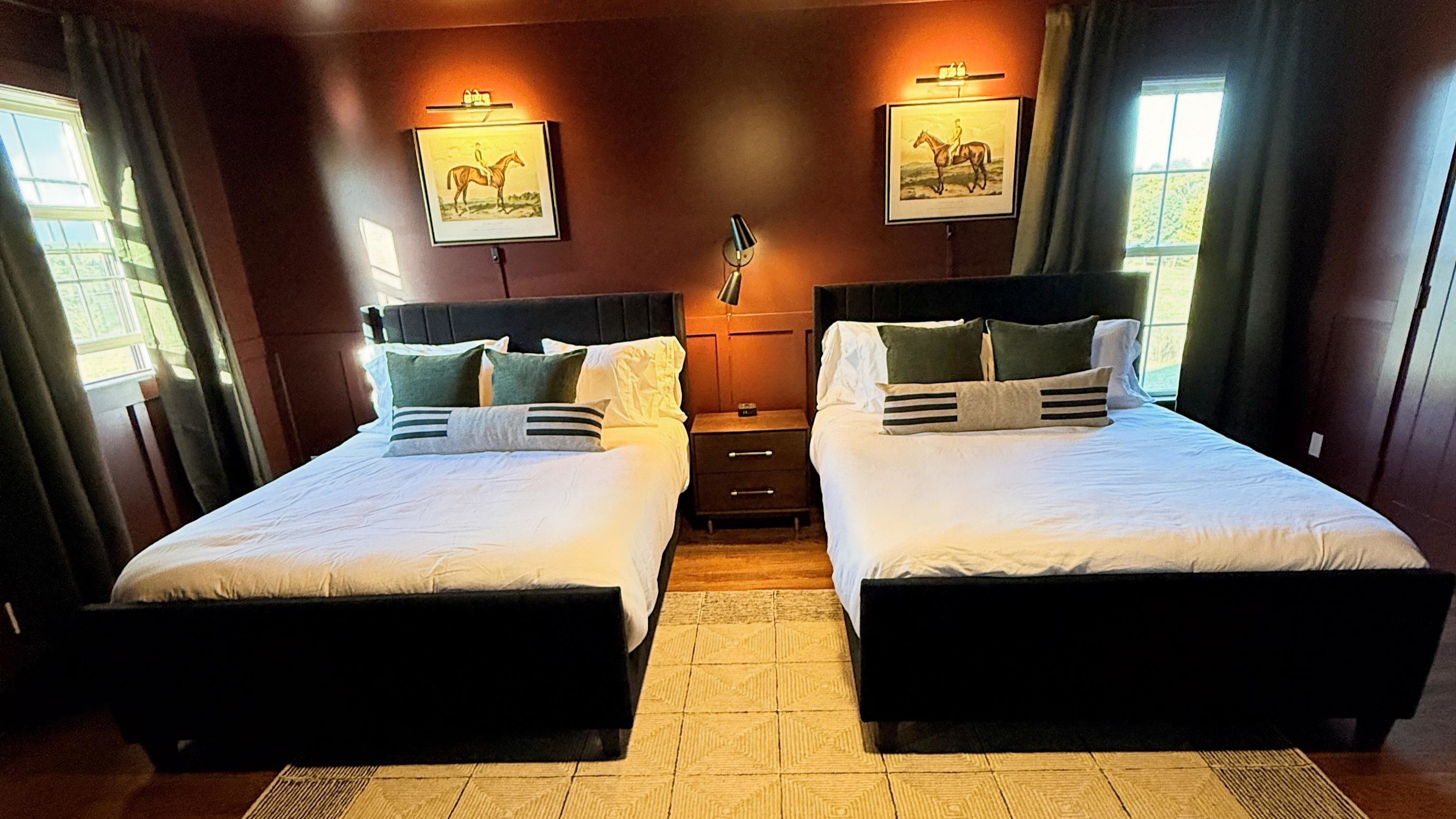 Bathed in rich auburn tones and soft, flattering light, this bedroom invites slow mornings and easy conversation — two queen beds set in refined textures and equestrian detail, offering a warm, subtly seductive sense of comfort and connection.