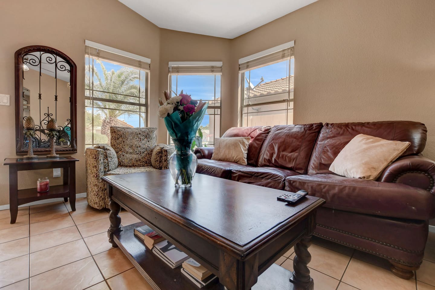 Sunny living room with leather sofa, bay windows & cozy seating
