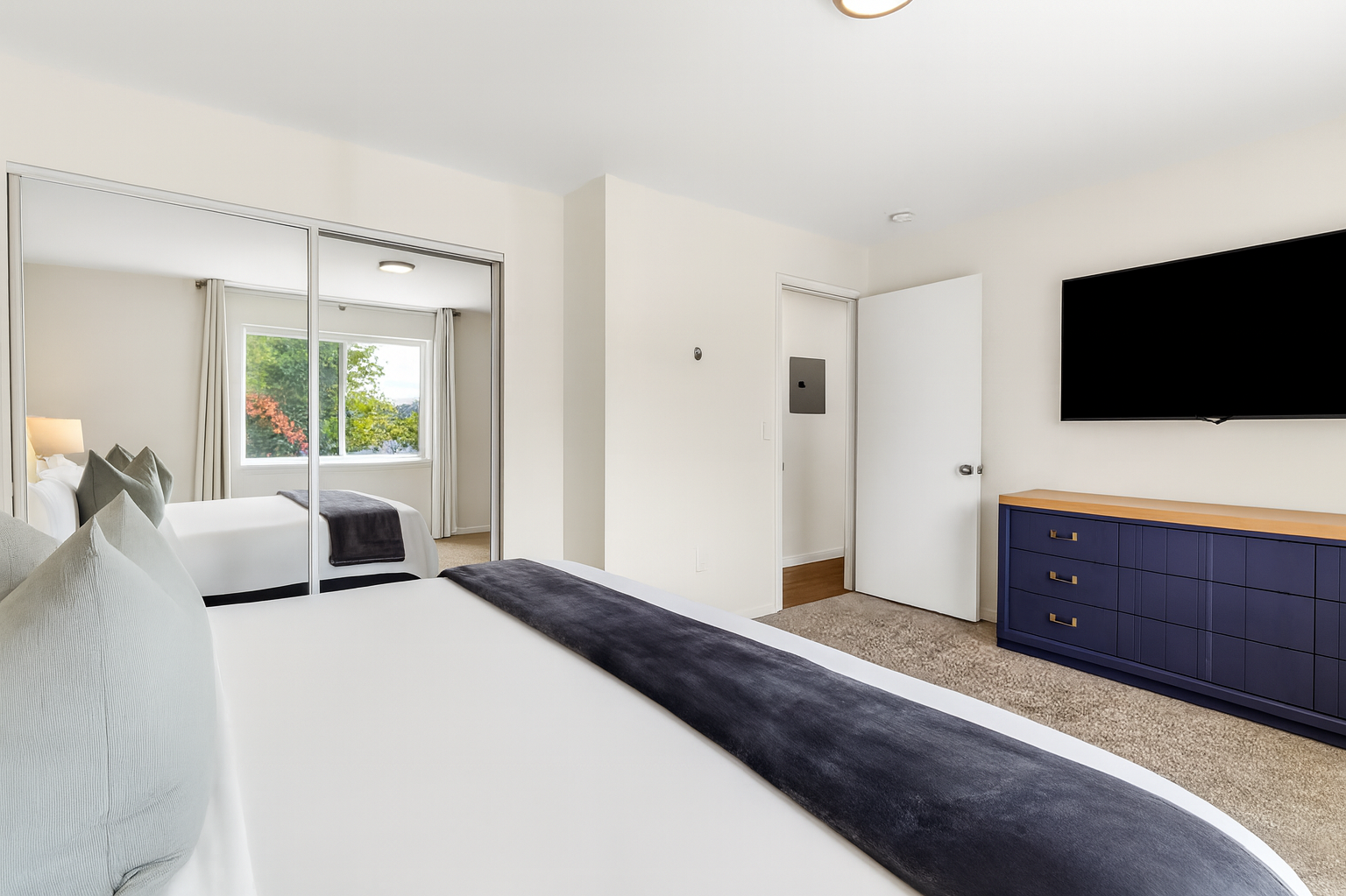 Full bedroom view with relaxing décor, blackout curtains, and private entertainment setup.
