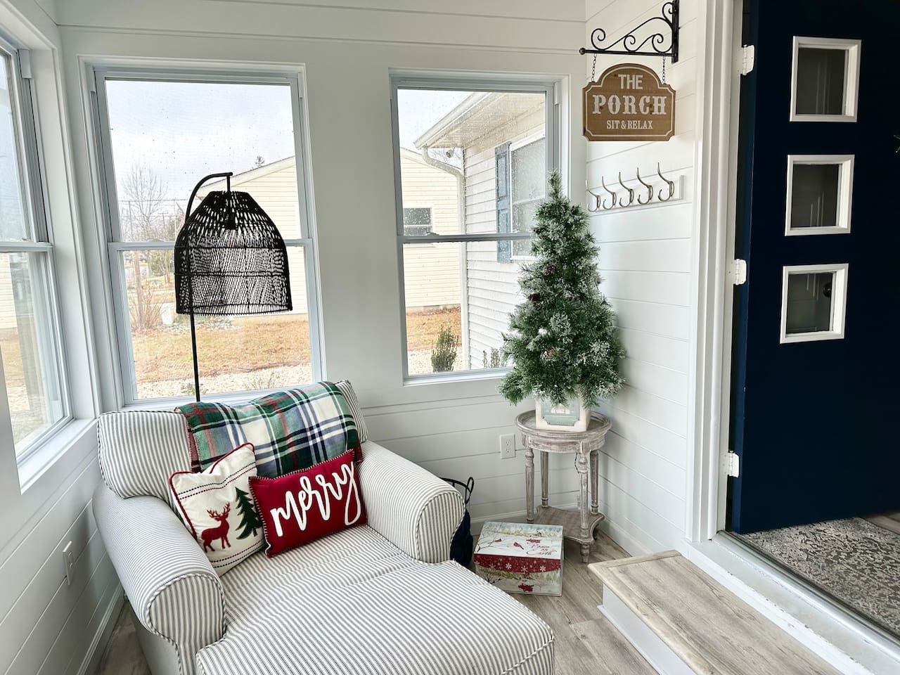 The holiday spirit extends into every corner of the home. In November, a bright sunroom is decked out for the season with a "Merry" pillow, a miniature flocked Christmas tree, and a comfortable striped chaise lounge—perfect for curling up with a blanket.