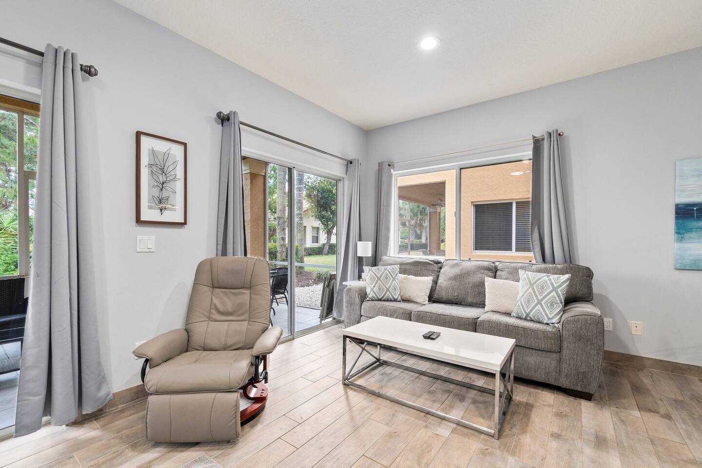 Stylish living room with cozy seating, recliner, modern flooring, and plenty of natural light.