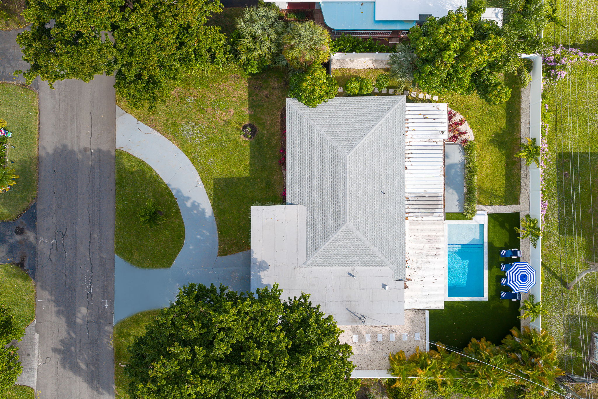 Soaring aerial perspectives highlight the home’s tranquil Pompano Beach neighborhood, private backyard oasis, covered carport, and extended driveway with space for 3 cars.