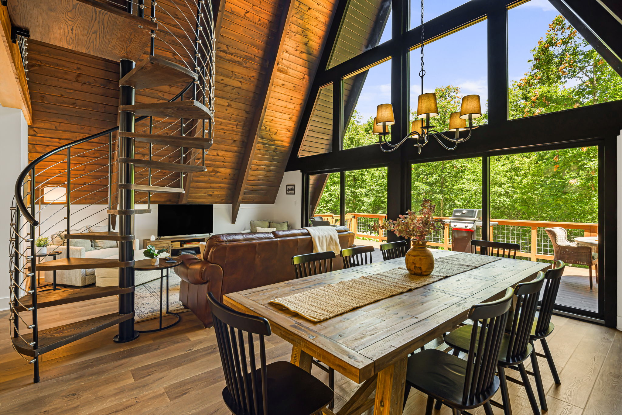 The heart of the cabin, where rustic charm meets modern comfort. With its soaring A-frame tongue & groove ceiling, and a full wall of windows this space is both stunning and cozy. Dramatic spiral staircase leads to the 2nd & 3rd floor spaces.