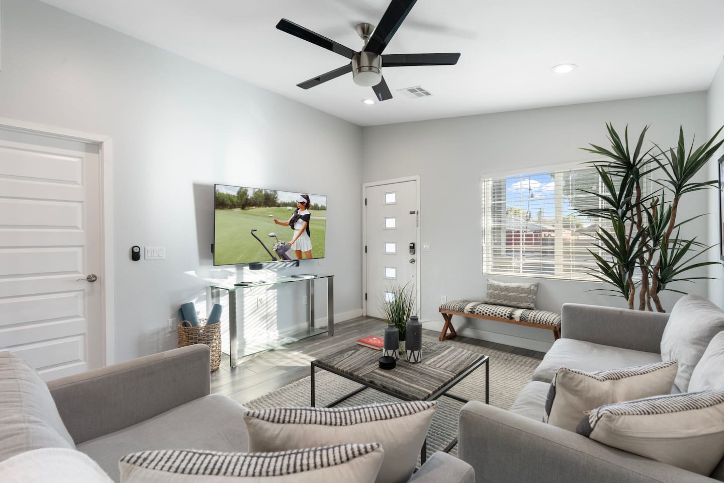 Bright and airy living room with large windows, cozy seating, and a sleek TV setup for your entertainment.