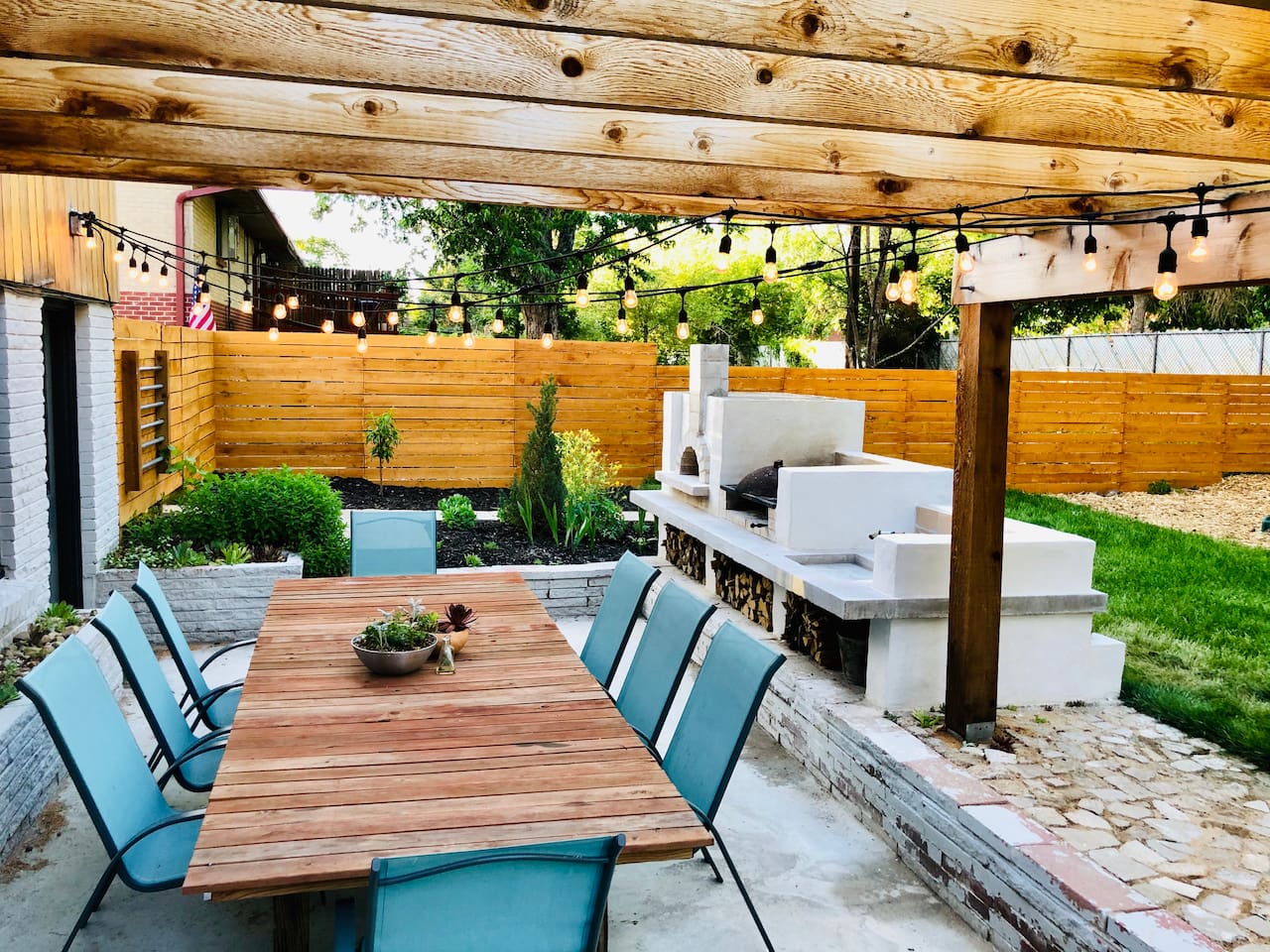 Backyard patio with outdoor kitchen and seating for eight under the twinkle lights