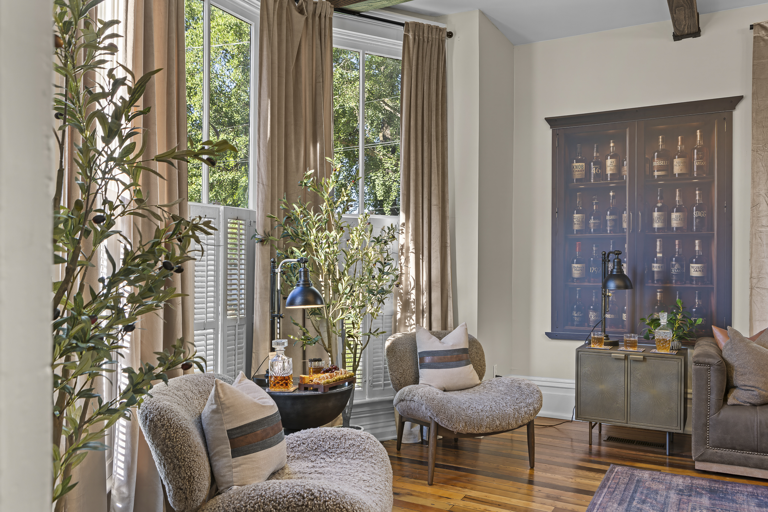 A quiet reading nook with a bourbon cabinet display, leather chairs, and just enough light to stay up too late.