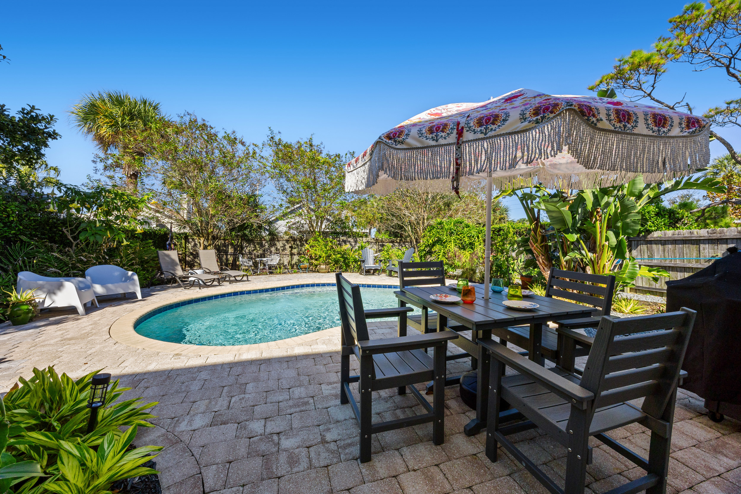 Outdoor Dining by the Pool
A shaded outdoor dining setup overlooking the pool, complete with colorful table settings and a decorative umbrella. Surrounded by tropical greenery, it’s the perfect spot for meals or cocktails in the sunshine.