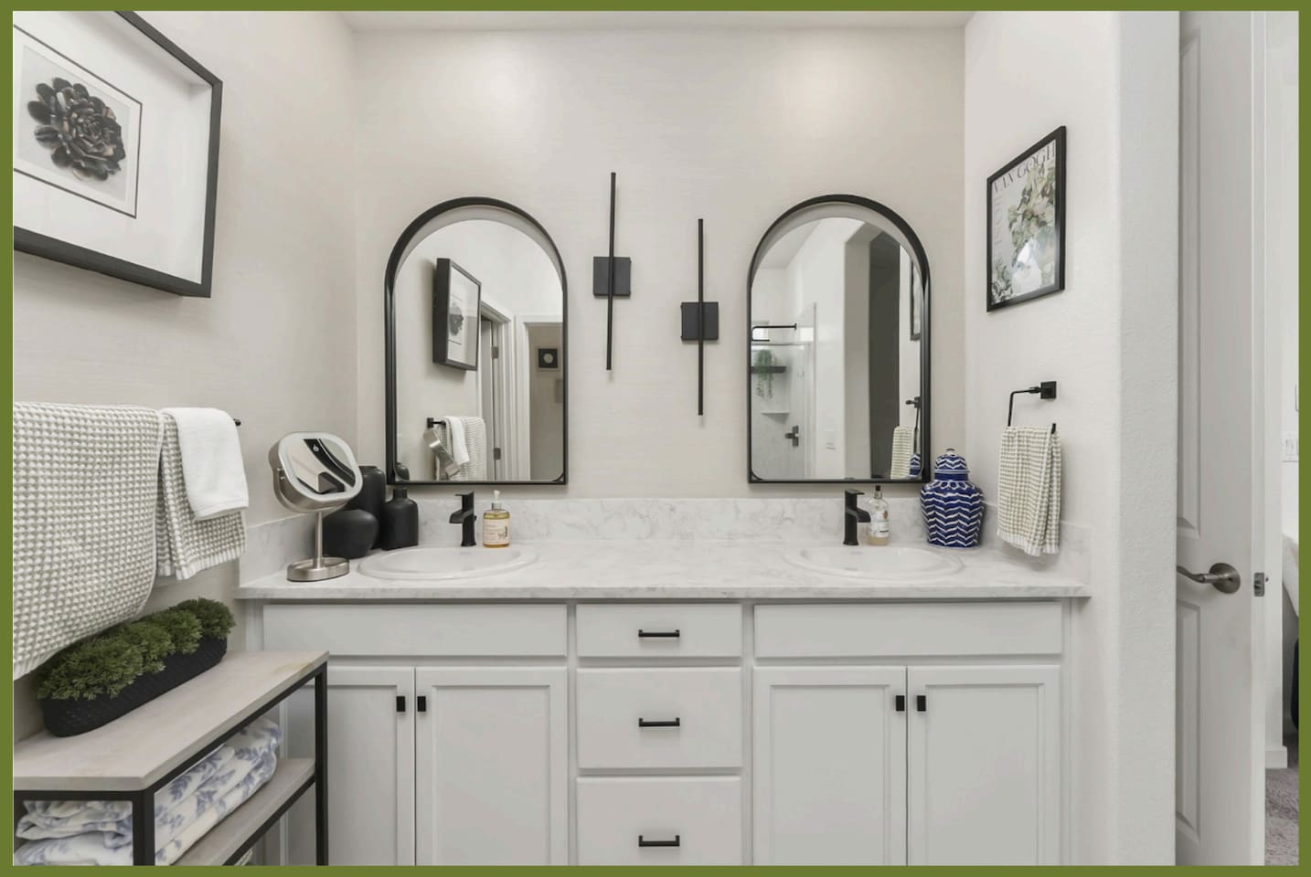 Bathroom vanity with double sinks, arched mirrors, storage drawers, and easy access from the nearby bedroom.