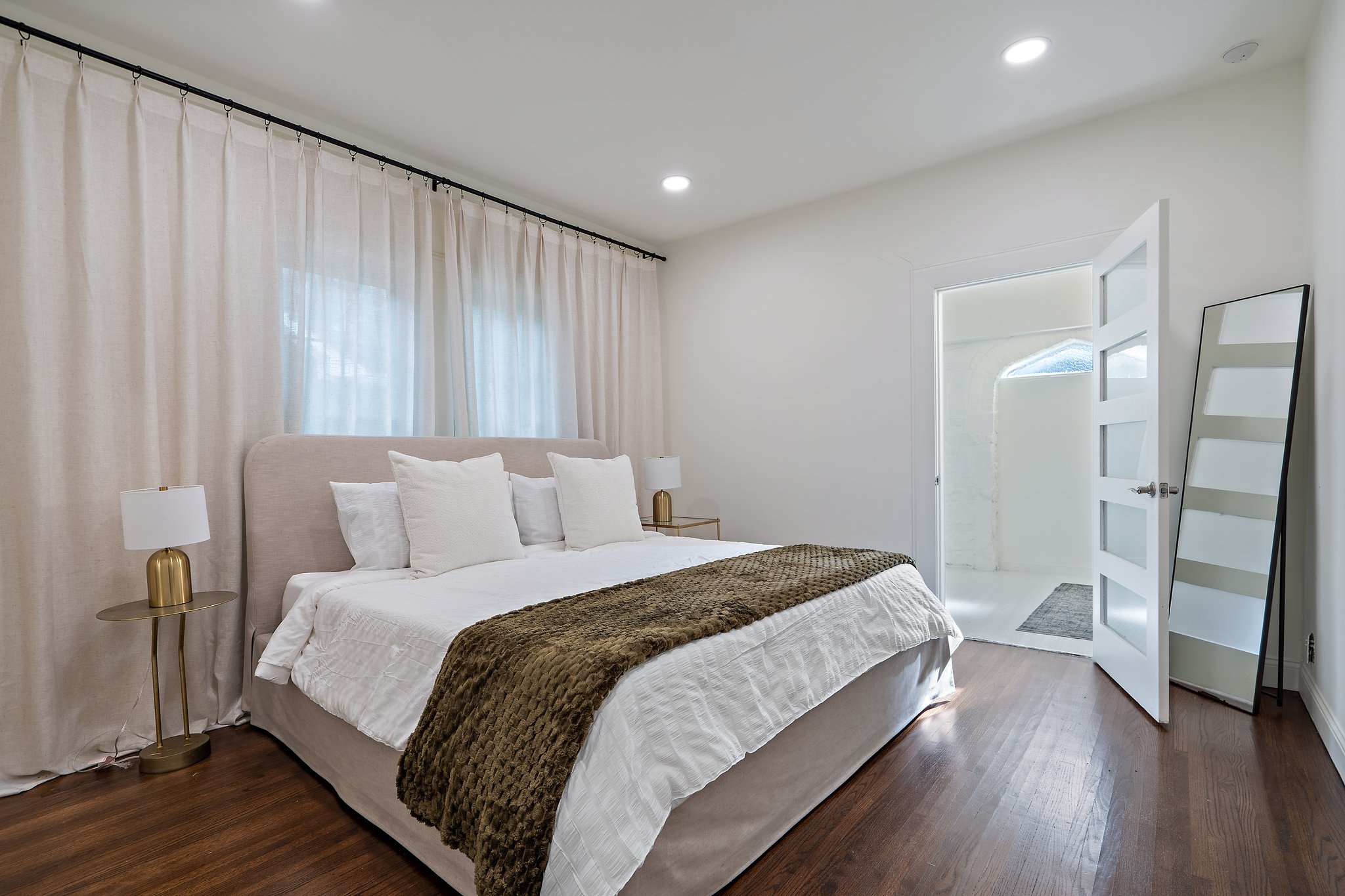Bedroom 1 King Bed with hotel-style linens, extra pillows and blankets, room-darkening shades, and clothing storage. Private space with central AC, ceiling fan, and high-speed Wi-Fi. First floor, main house.