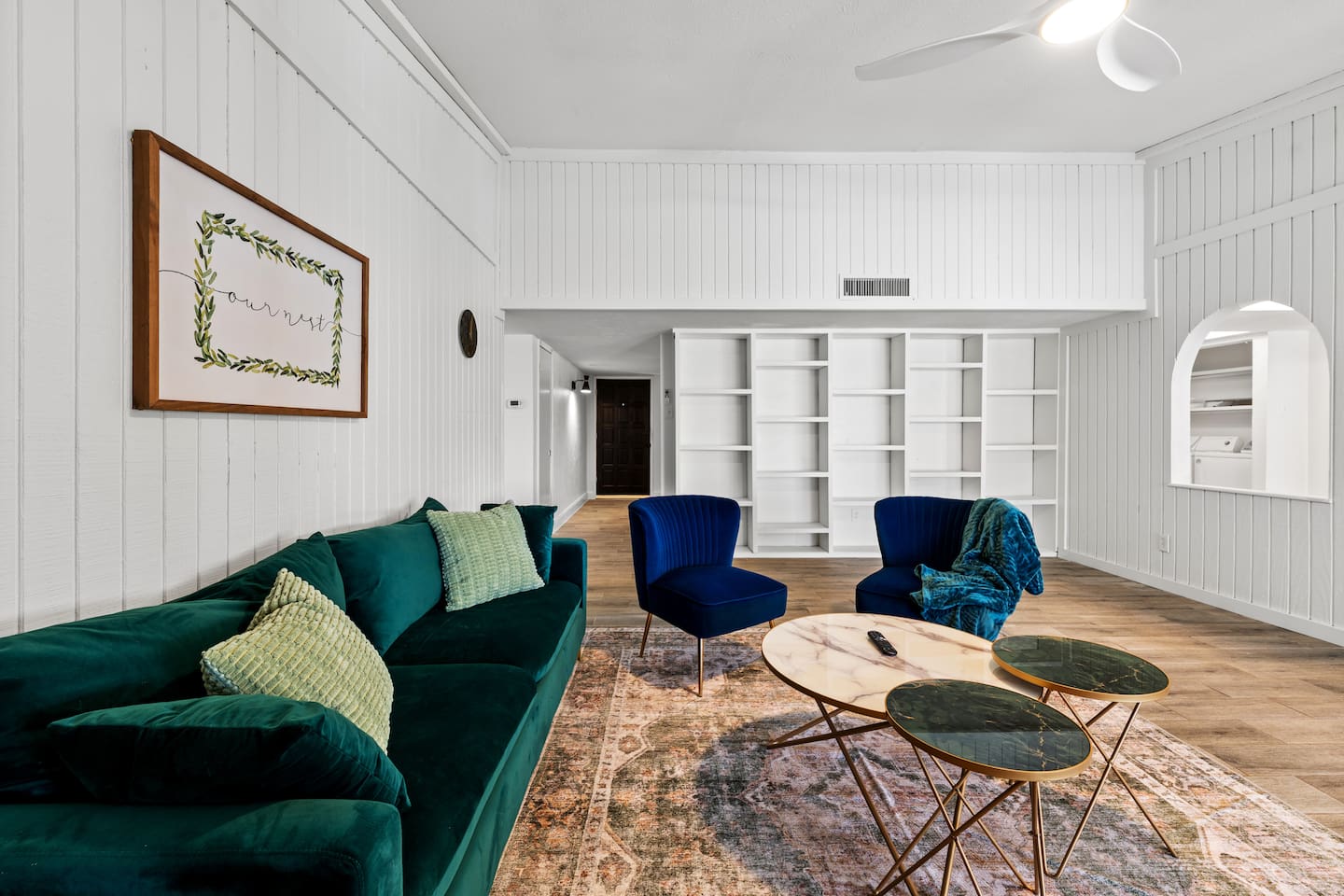 Chic and cozy living room with vibrant velvet seating, statement decor, and open shelving—perfect for relaxing or hosting in style.