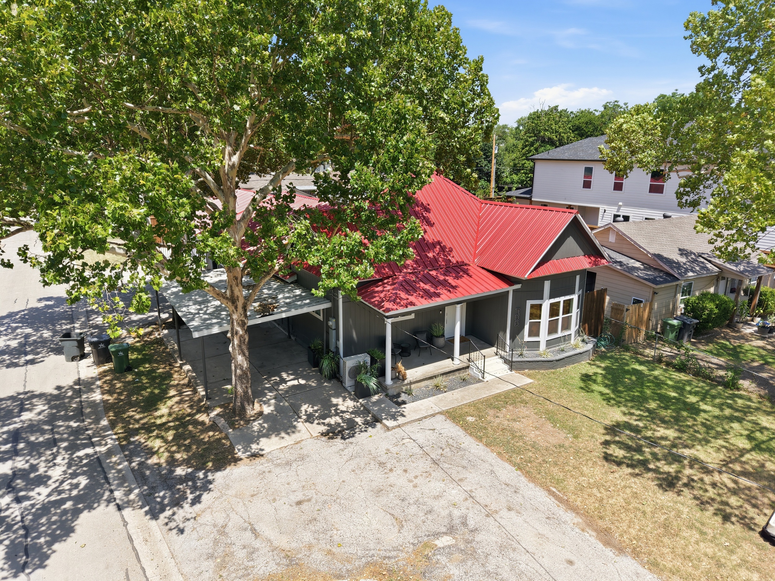 Charming home with vibrant red roof, shady trees, and inviting outdoor space awaits!