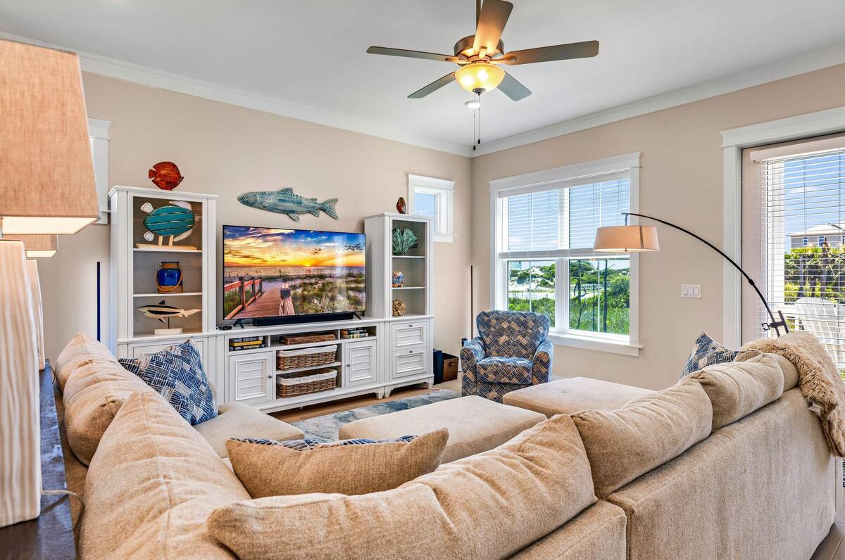 Sink into coastal comfort in this sunlit living room, featuring plush seating, charming beach décor, and a smart TV perfect for movie nights or game days.