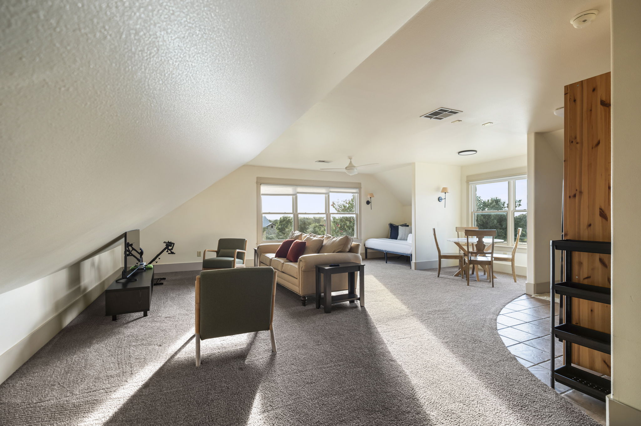A private and spacious apartment above the garage featuring a queen daybed, a TV, two armchairs, and a three-person sofa for comfortable lounging.
