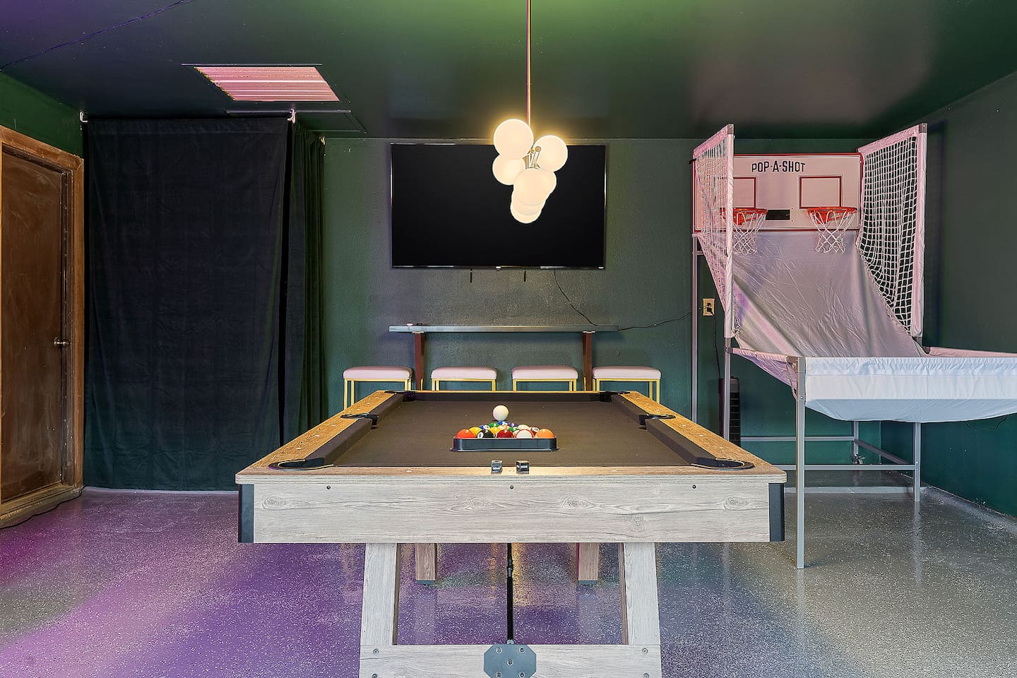Explore this vibrant game room featuring a modern pool table, ample seating, and stylish lighting. Additional entertainment with an arcade basketball setup.