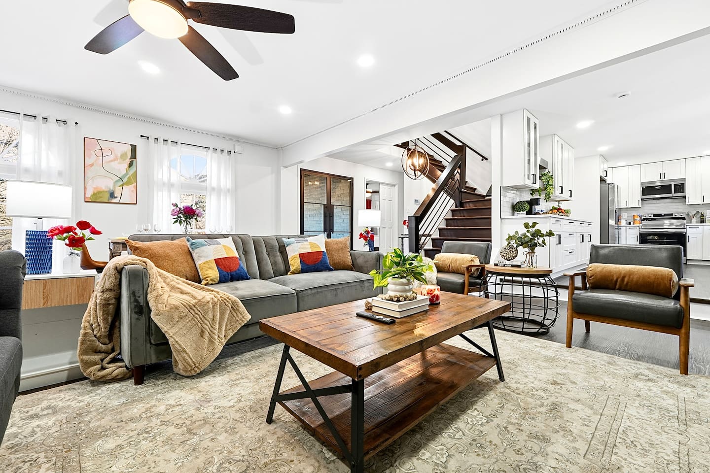 Warm and welcoming living room with two comfortable couches, two chairs, indoor plants, a cozy fireplace, and a TV powered by Google TV. Conveniently located as you walk through the front door and straight ahead from the primary side entrance. 