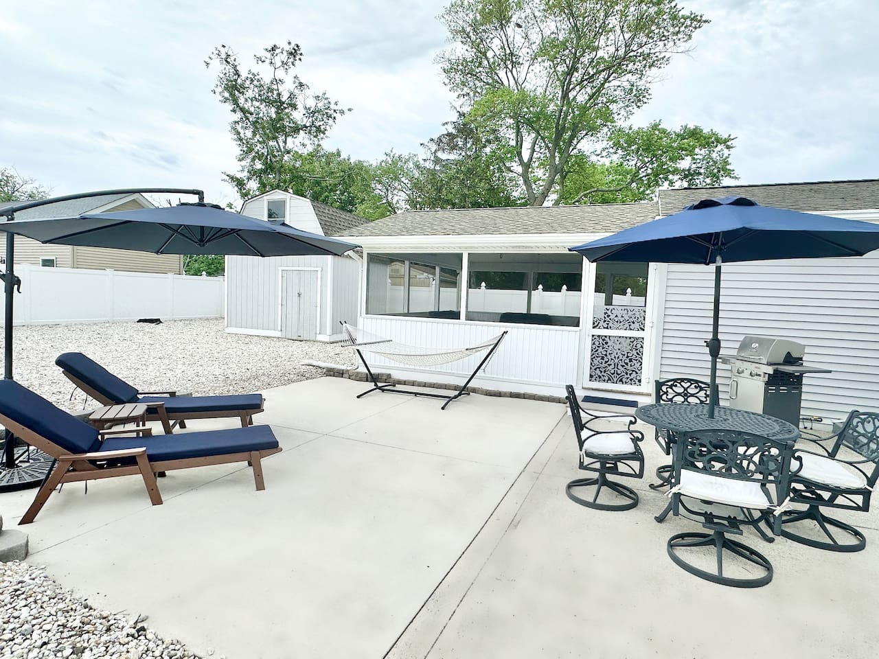 Make the most of the sunshine on our spacious concrete patio. This versatile outdoor space features comfortable navy lounge chairs, large umbrellas, a relaxing hammock, and a dining set with a grill—perfect for hosting summer BBQs and fresh air.