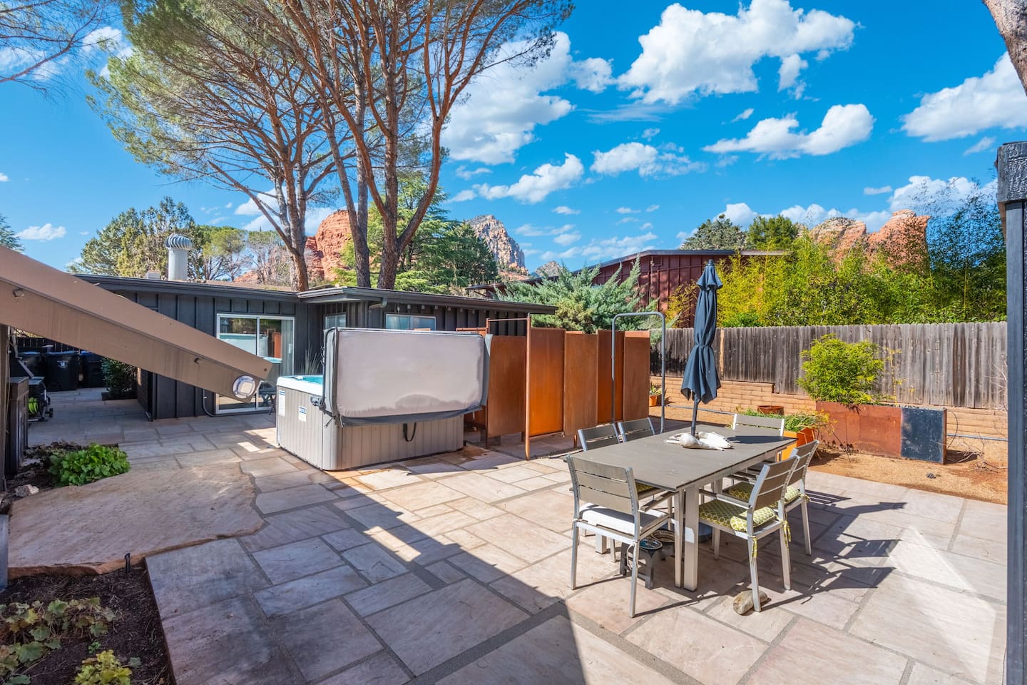 Private backyard oasis featuring a hot tub, outdoor dining area, and scenic red rock views — the perfect setting for relaxing evenings and sunny desert afternoons.