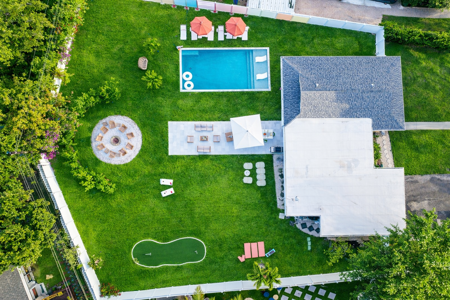 Private Palm Beach backyard with heated saltwater pool, fire pit, mini golf putting green, and outdoor lounge seating.