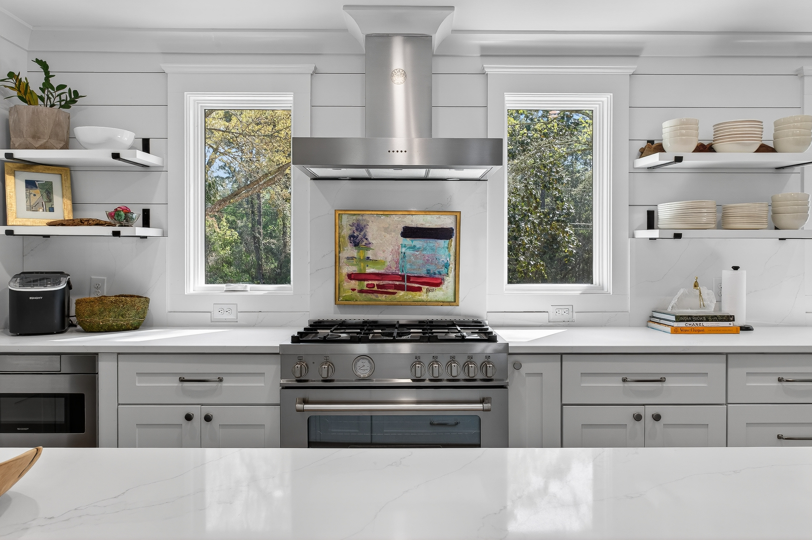 Bright, designer kitchen with chef’s range, quartz counters, and shelving—beautifully equipped for cooking or gathering at home