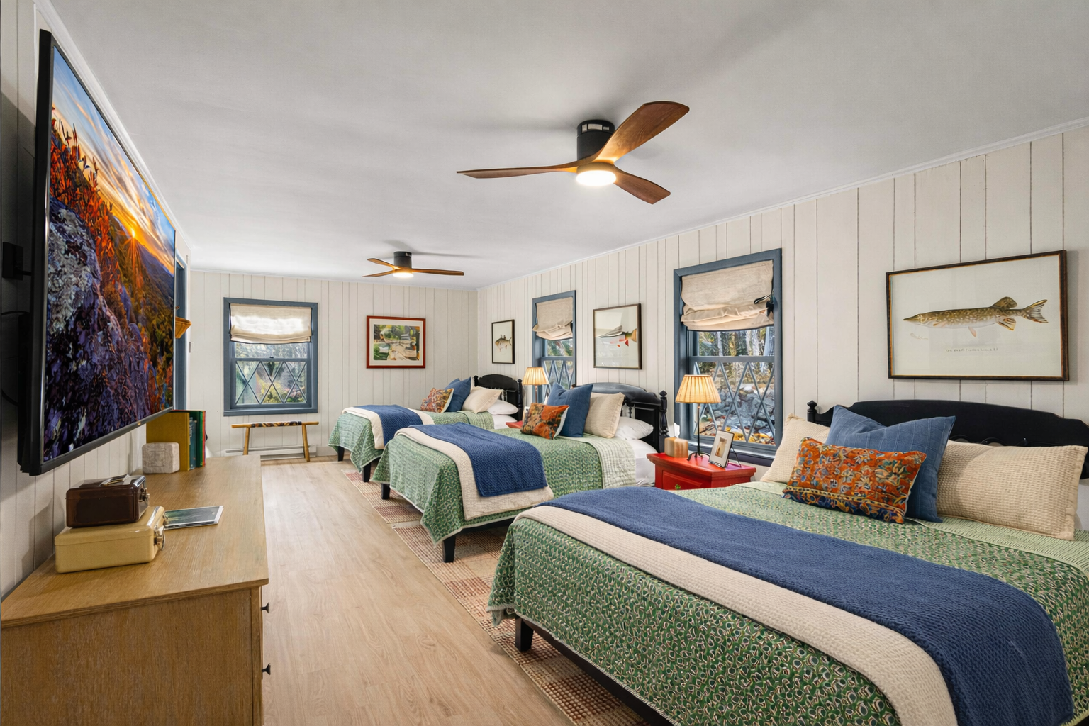 The Fisherman’s Room features three queen beds in a spacious, private bedroom tucked away from the rest of the home. This retreat includes an ensuite bathroom and a cozy reading/TV nook that wraps around the back left side of the room—perfect for relaxing