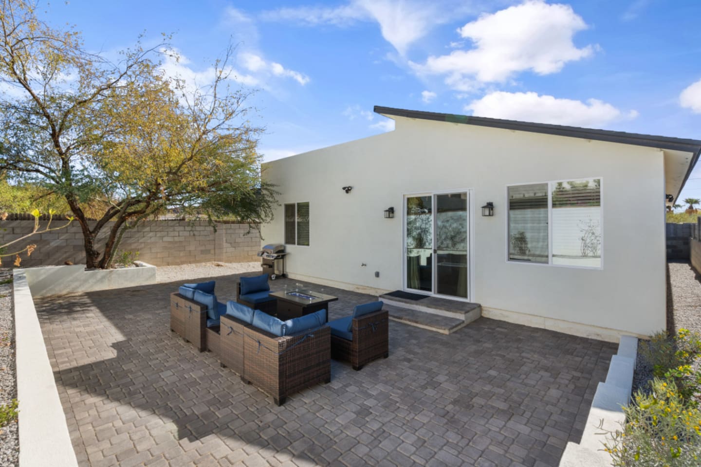  Private patio with outdoor lounge seating, BBQ grill, and a spacious paved area for relaxing outside.