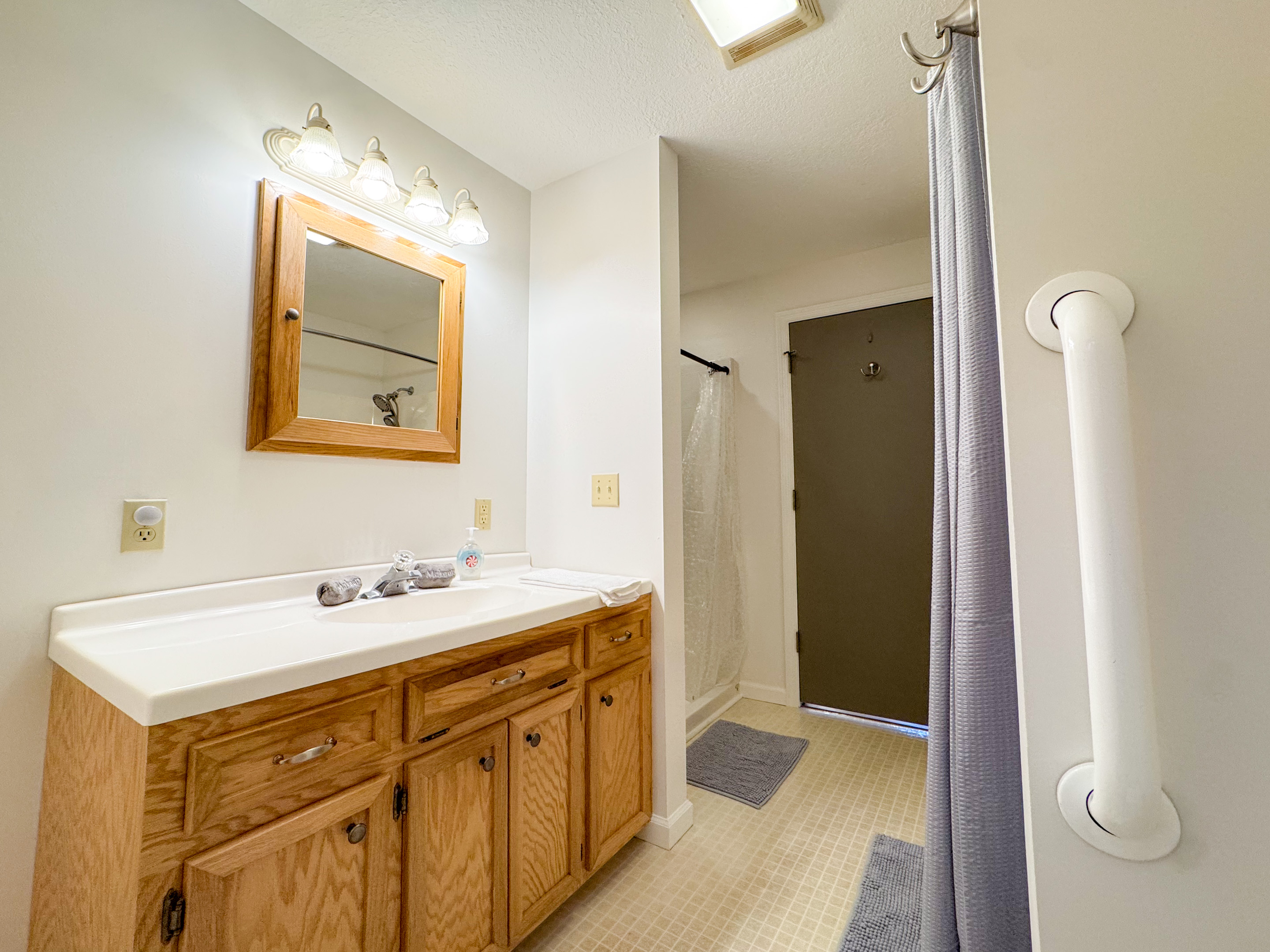 The ensuite bathroom features a tub/shower combination, toilet, vanity, grab bars, and a separate stall shower with low clearance! A rare treat!