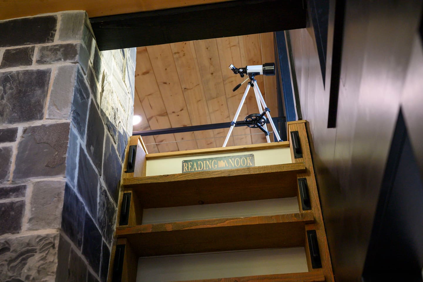 Climb the ladder beside the upper-level fireplace to discover a hidden stargazing lounge tucked high above the cabin.