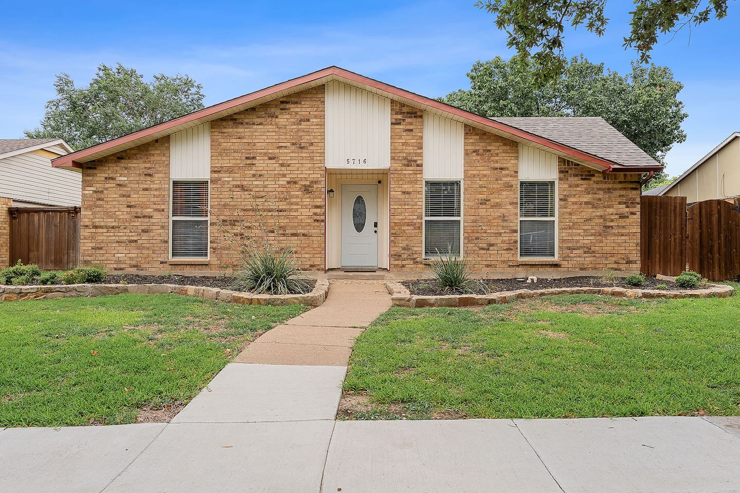 Admire the inviting facade of this brick home, complete with a neatly manicured garden and a cozy front entrance.