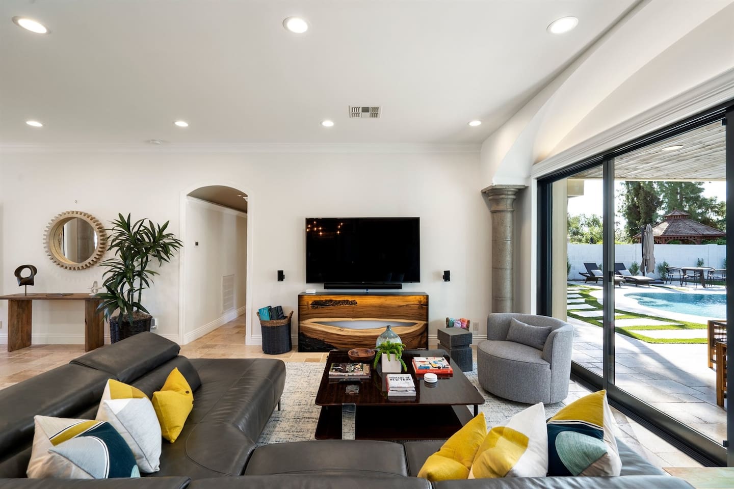 Where comfort meets entertainment! Enjoy picturesque views of the pool from our stylish living room, complete with a spacious black sofa and a large TV equipped with Sonos speakers. Your dream getaway awaits!
