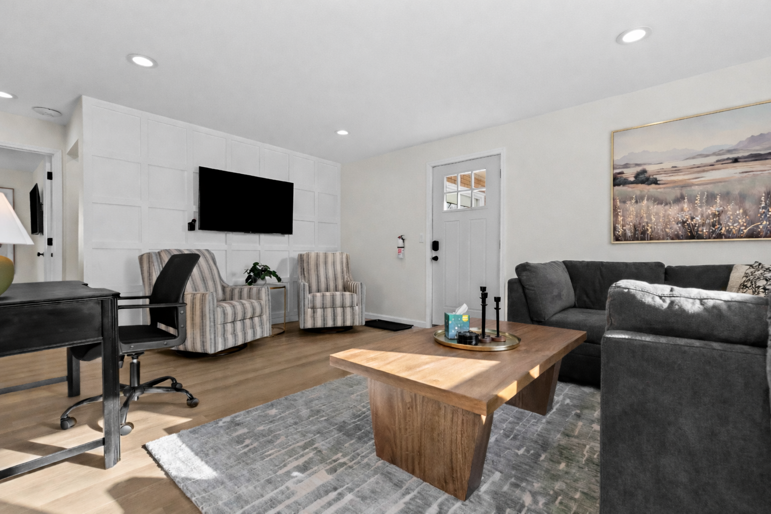 Relax in this sun-filled living room featuring plush seating, a smart TV, and a dedicated workspace—designed for comfort, productivity, and easy unwinding.