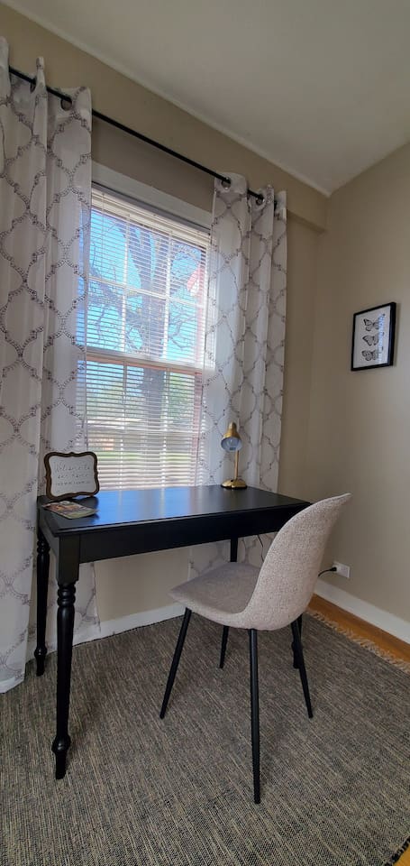 Bright and welcoming workspace with a cozy chair, desk lamp, Wi-Fi info, and natural light—perfect for remote work or planning your stay.