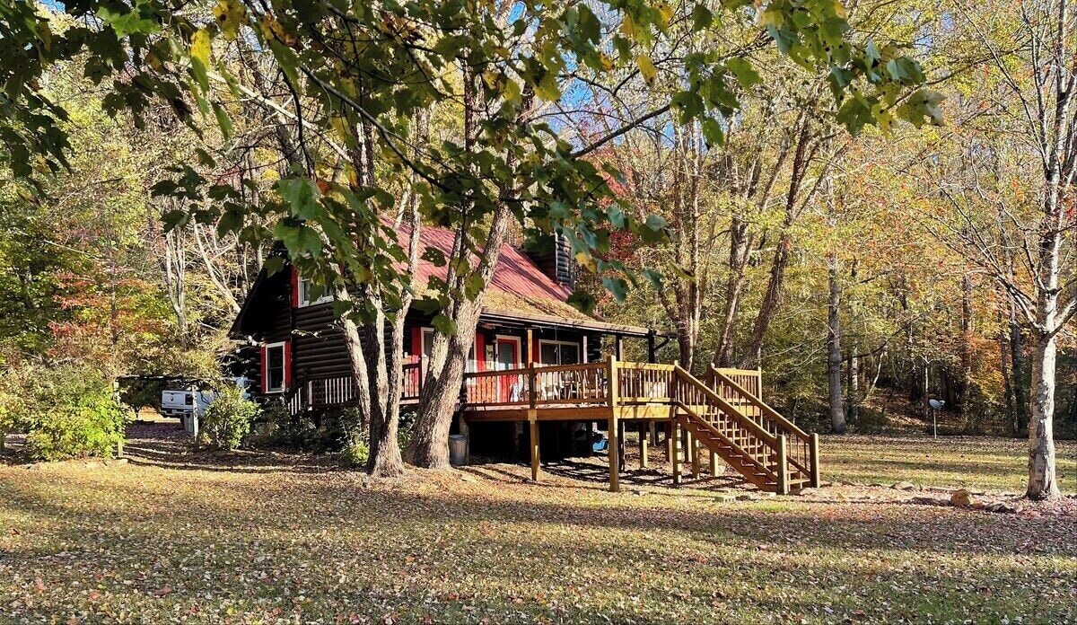 View of the exterior. The deck has the hot tub, grill, and dining table on it and faces the pond.