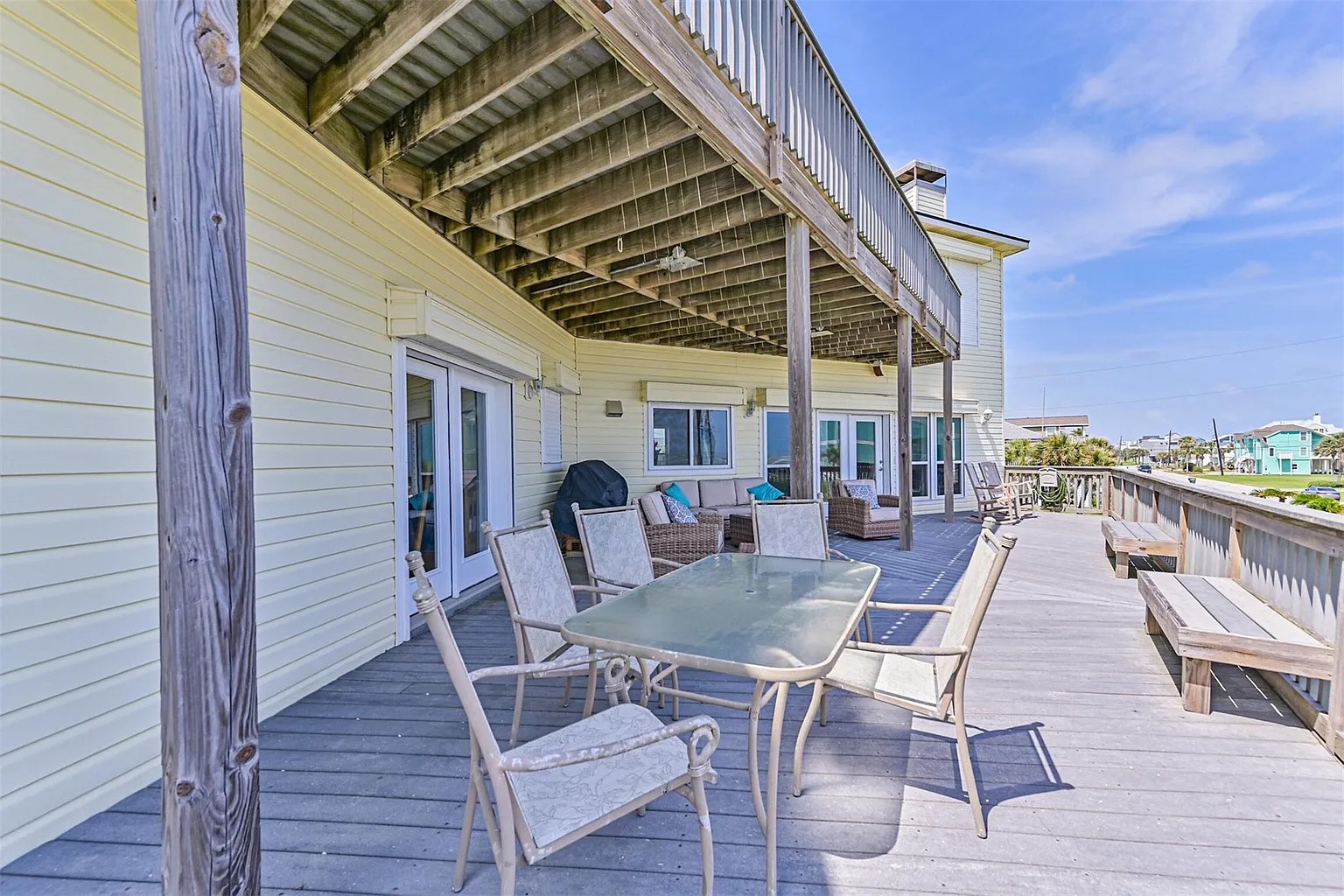 Covered deck with dining, lounge chairs, and propane grill