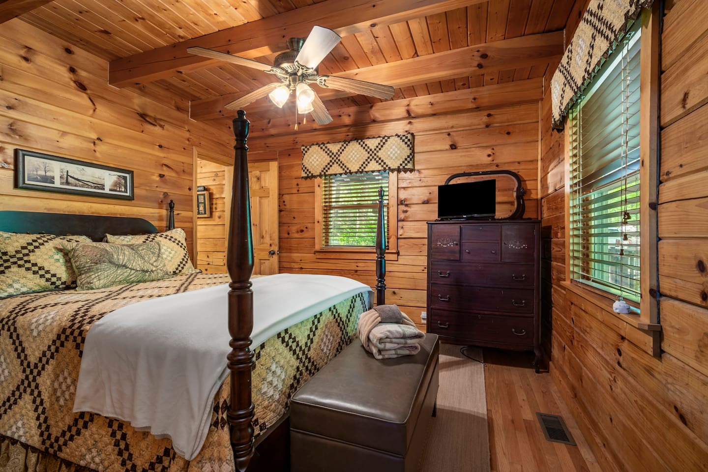 Cozy second bedroom with charming, rustic decor, warm wood interiors, and a comfortable four-poster queen bed.