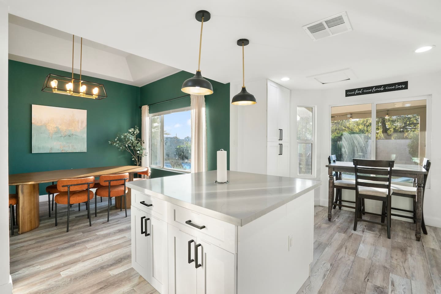 Multi-zone room with forest green accent wall, chef's island, workspace, and scenic window views.
