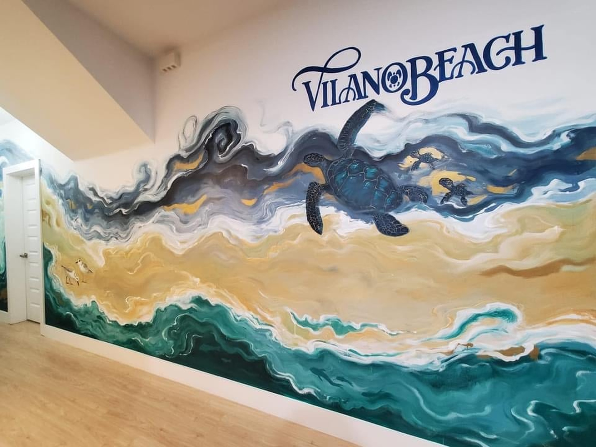 An artist painted this wall by hand - turtles, sandpipers, and the Atlantic rolling in beneath the words Vilano Beach. It is the sort of detail that tells you the people who built this house love the place.