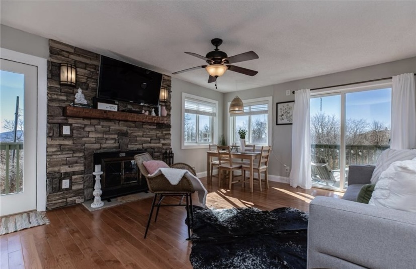 Cozy living room with wood burning fireplace and door leading to balcony. Open-concept living space—perfect for relaxing together