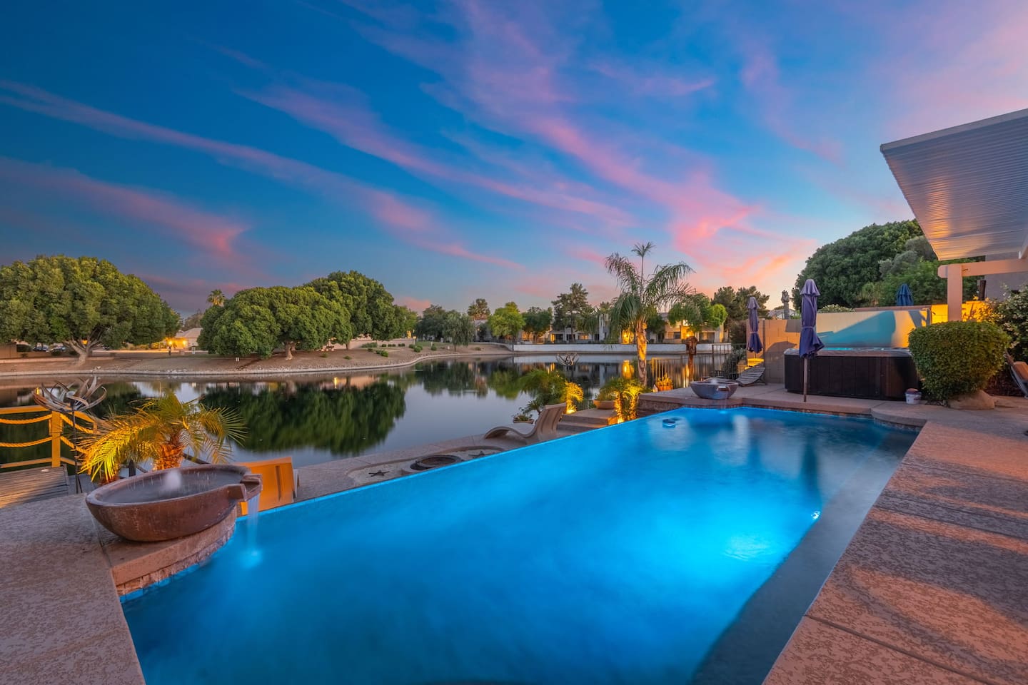 The pool glows electric blue as the desert sunset melts into the lake — an evening scene that makes it impossible to go inside.