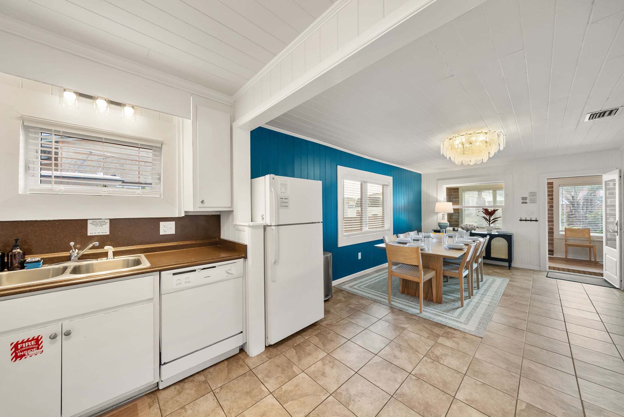 The open-plan kitchen and dining area flow together so the cook is never cut off from the conversation. White cabinets, full appliances, and a clear sight line to the table.