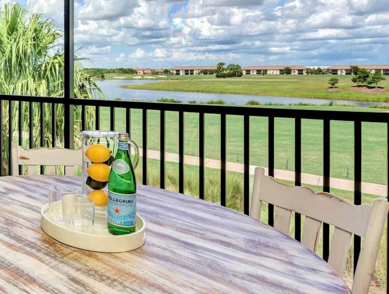 A serene balcony scene overlooking a golf course with palm trees.
