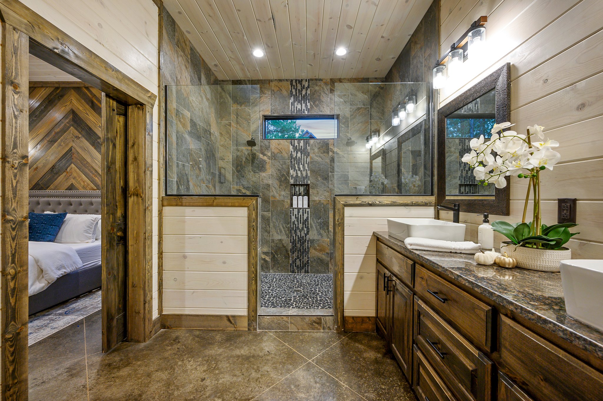Spa-like master bath featuring dual vanities and modern stone tiling.