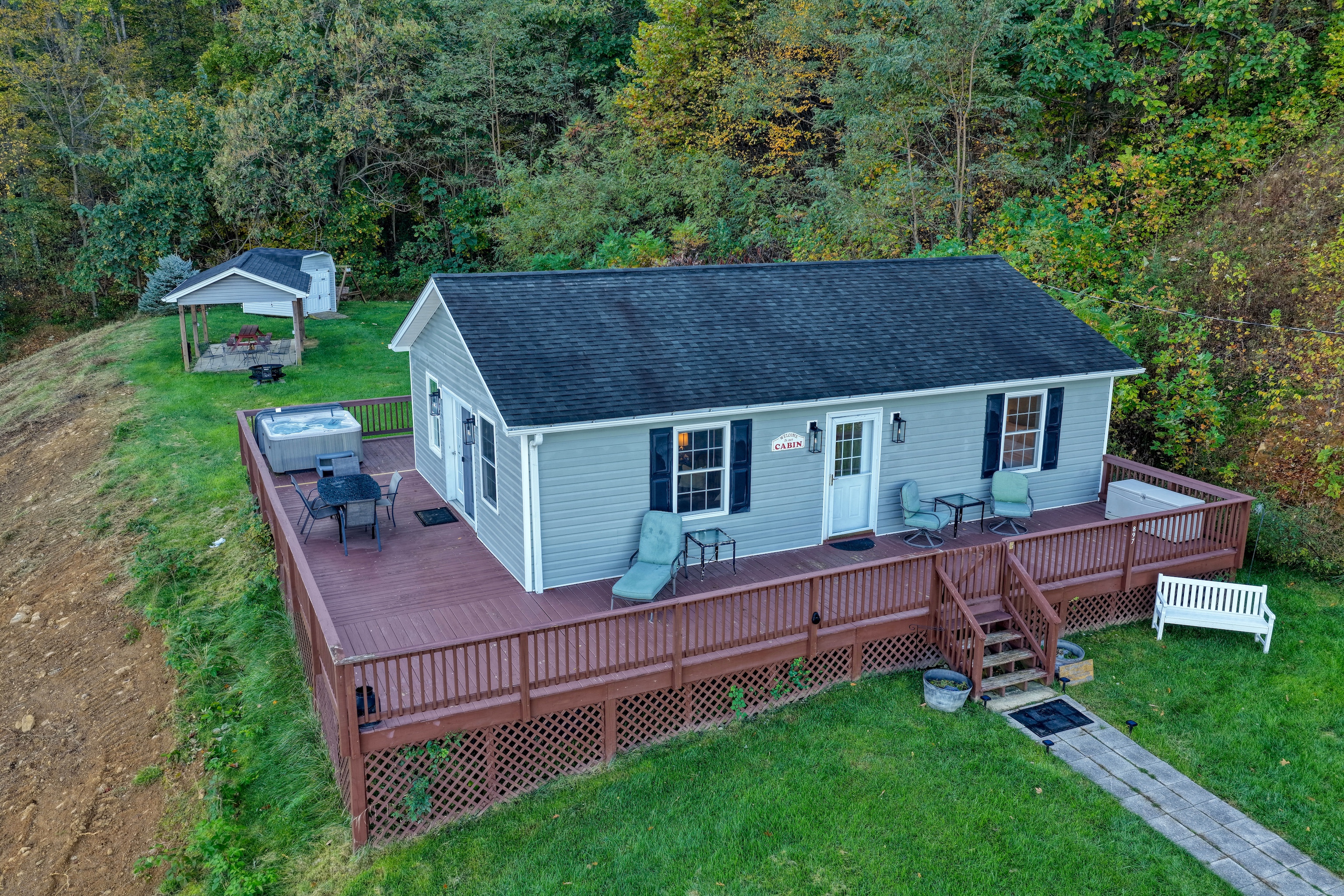 An aerial view of the front year, deck, and back yard from the front.