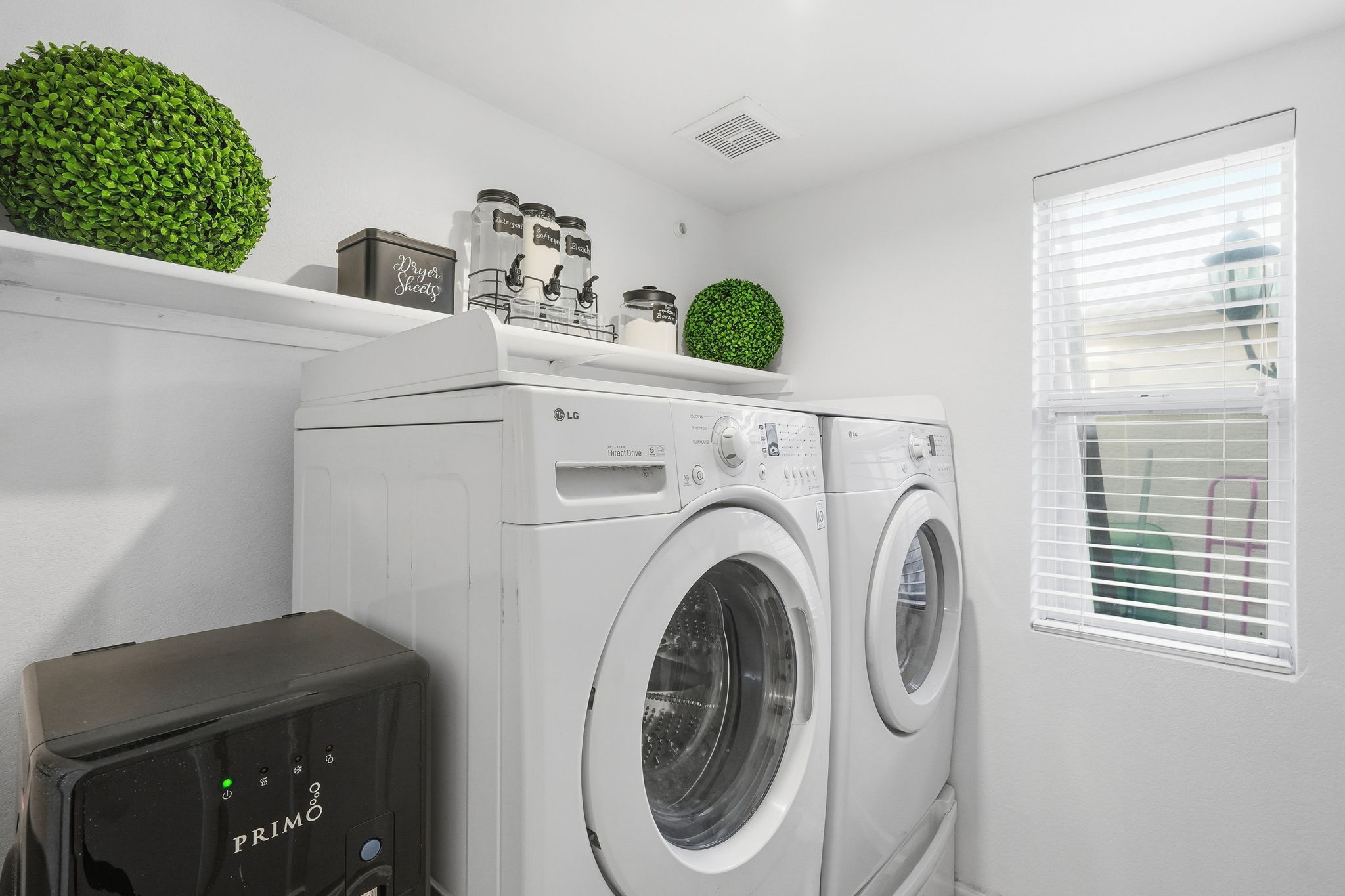 Laundry area with washer, dryer, natural light, and detergent supplies for added convenience during your stay.