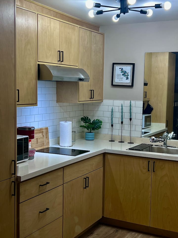 Kitchenette corner with wood cabinets, cooktop, sink, and space for simple meals.
