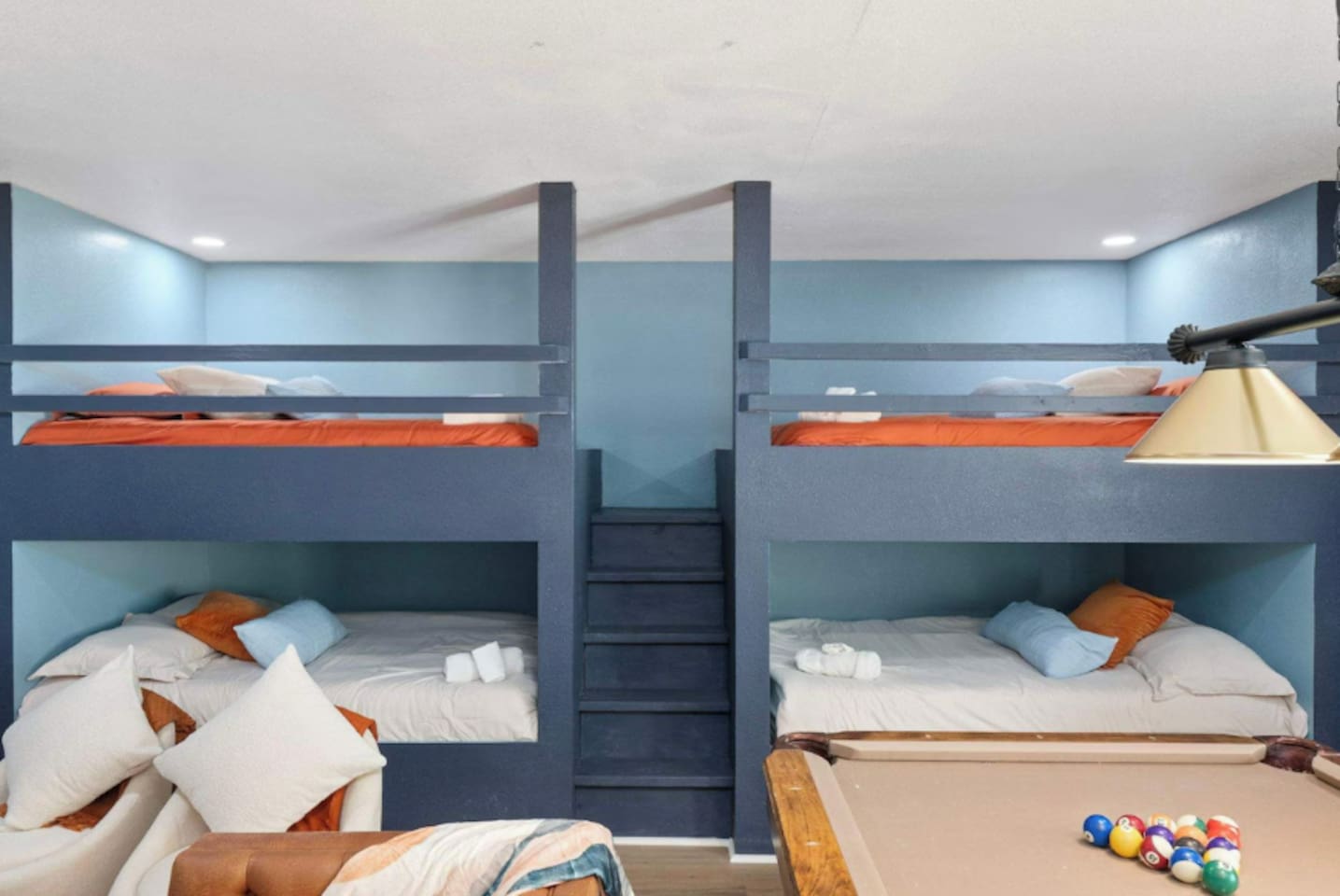 Bunk room with quad bunks, blue walls, and orange accents—sleeps up to eight guests comfortably for large groups.