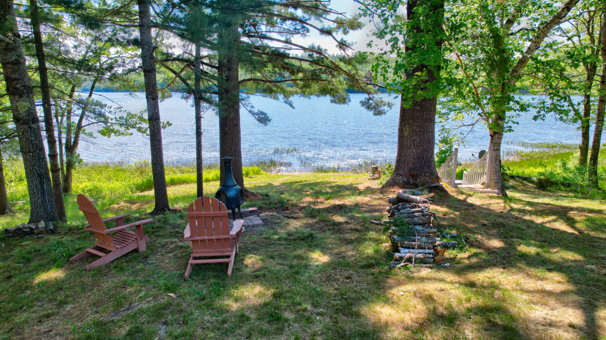 Chimnea and chairs facing the lake behind the log cabin