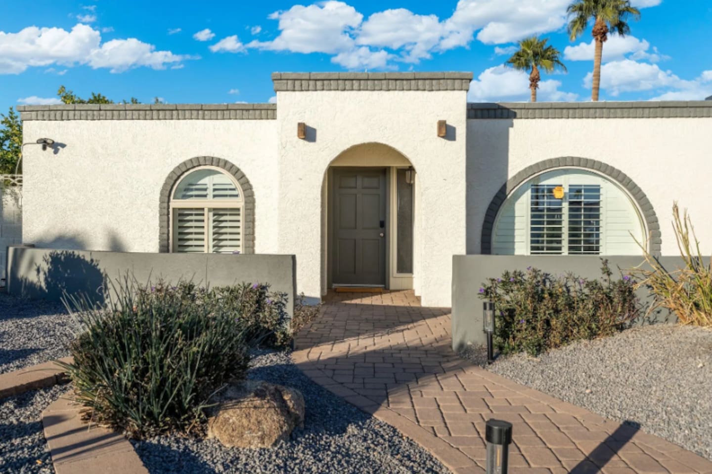 A striking arched entry framed by desert landscaping sets the tone before guests even step inside, low-maintenance and effortlessly stylish.
